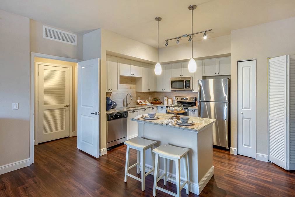 a kitchen with an island and a stainless steel refrigerator